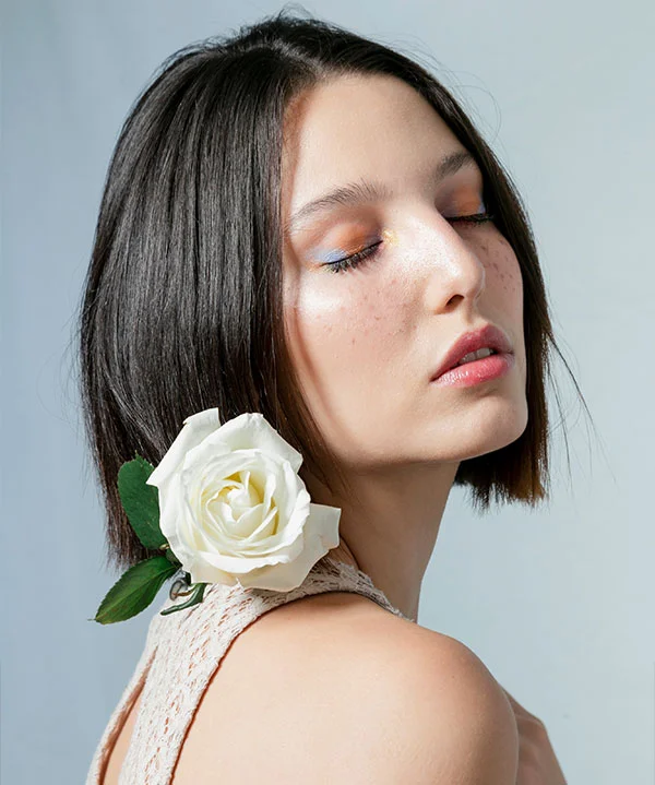 A woman with glowing makeup and a white rose symbolizing natural beauty and rejuvenation.